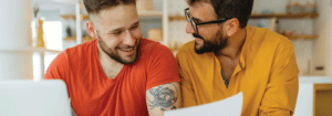 Two men working together and smiling at one another.